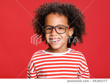 Happy curly boy in striped t-shirt on color red background Happy curly boy in striped t-shirt on color red background 94260377