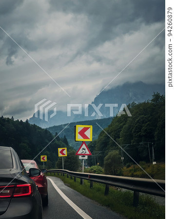 Car moving on a serpentine roadway between the mountains 94260879