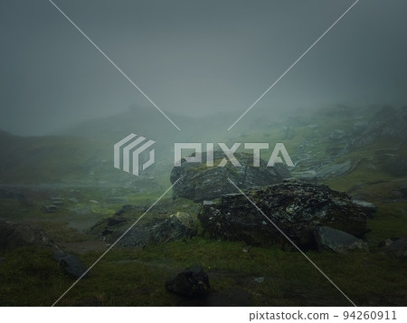 Big mountain rocks and boulders seen through the dense mist. Moody hiking scene with rainy weather Big mountain rocks and boulders seen through the dense mist. Moody hiking scene with rainy weather 94260911