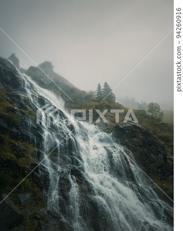 Capra waterfall on the Transfagarasan winding route of Carpathian mountains, Romania. Wonderful landscape with a tumultuous river flowing down through the cliffs in a foggy autumn morning Capra waterfall on the Transfagarasan winding route of Carpathian mountains, Romania. Wonderful landscape with a tumultuous river flowing down through the cliffs in a foggy autumn morning 94260916