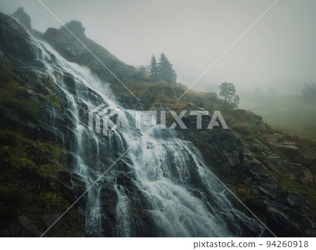 Capra waterfall on the Transfagarasan route in romanian Carpathians. Idyllic scene with a big river flowing down through the rocks in a misty autumn morning Capra waterfall on the Transfagarasan route in romanian Carpathians. Idyllic scene with a big river flowing down through the rocks in a misty autumn morning 94260918
