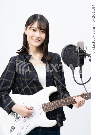 年輕女子一邊彈電吉他一邊唱歌 94261194