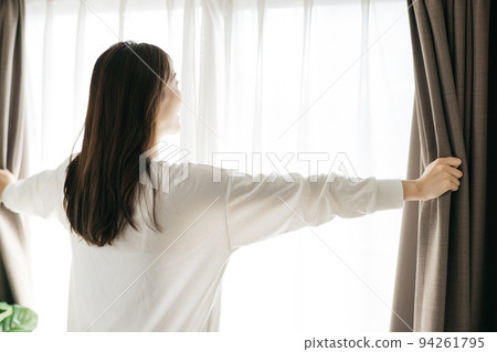 Woman opening the curtain, wake-up image Woman opening the curtain, wake-up image 94261795