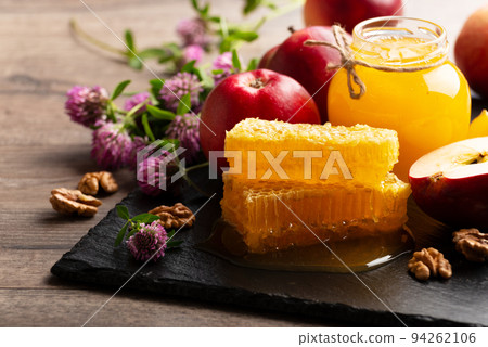 Mason jar with honey, honeycomb, red apples and walnuts on kitchen table Mason jar with honey, honeycomb, red apples and walnuts on kitchen table 94262106