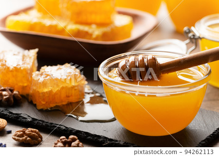 Honeycomb on slate tray with honey and nuts on kitchen table 94262113