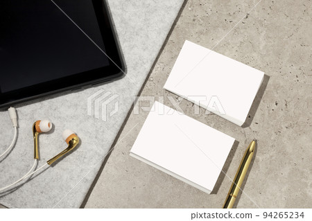 Blank white business cards on table with pen, digital tablet and earphones. Mockup for branding identity. Possibility to show both sides of card. Template for graphic designers. Free space, copy space Blank white business cards on table with pen, digital tablet and earphones. Mockup for branding identity. Possibility to show both sides of card. Template for graphic designers. Free space, copy space 94265234