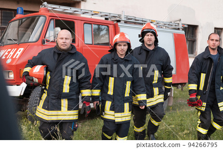 Group of fire fighters standing confident after a well done rescue operation. Firemen ready for emergency service.  94266795