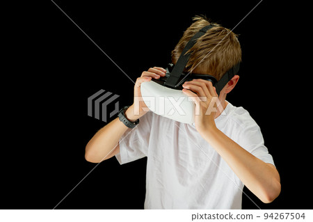 Portrait of young boy playing VR game in black background. Young hipster wearing VR headse 94267504