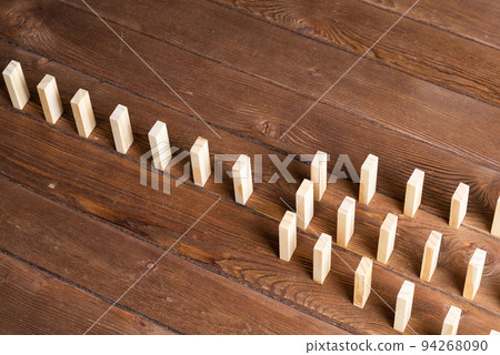 Rows of dominoes standing on wooden table 94268090
