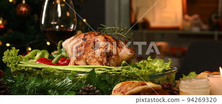 Thanksgiving table or Christmas dinner roasted turkey, glass of red wine all sides dishes in decorated room with a Christmas tree 94269320