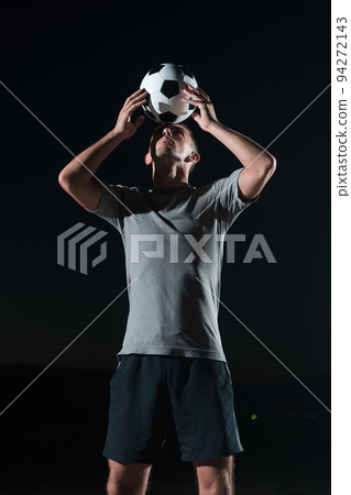 portrait of a young handsome soccer player man on a street playing with a football ball. 94272143