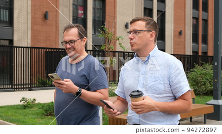 attractive men going on street in urban city center in smart casual business style, talking, working together, smiling, stylish freelance people 94272897