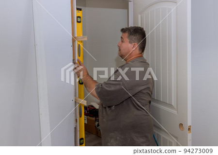 An interior door installation is carried out by a carpenter trim worker in a new house 94273009