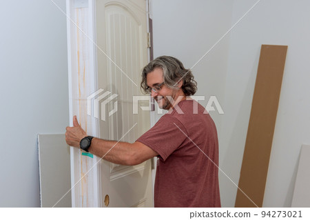 The worker holds the door in preparation for installation in a new house 94273021