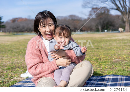 Parents and children relaxing on the lawn square in the park 94274184