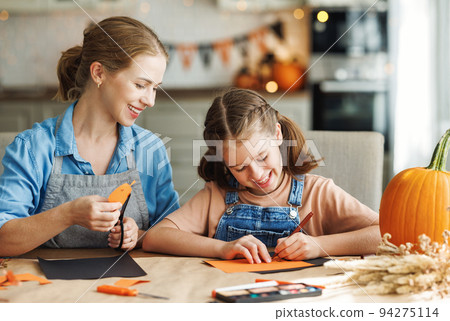 Happy smiling family mother and daughter making Halloween home decorations together 94275114