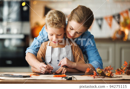 Happy smiling family mother and son making Halloween home decorations together Happy smiling family mother and son making Halloween home decorations together 94275115