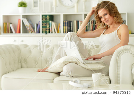Portrait of a beautiful woman with a laptop on the sofa Portrait of a beautiful woman with a laptop on the sofa 94275515