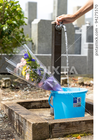 一位來掃墓的老人正在往桶裡倒水 94275570
