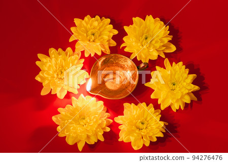 Diwali Indian Light Festival. Diya oil lamp and yellow flowers on red background. Traditional Hindu celebration. 94276476