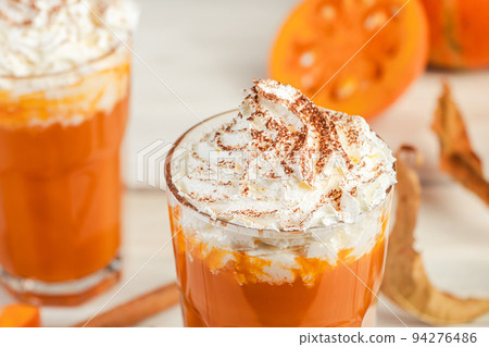 Pumpkin latte with whipped cream on light wooden background. Hot spicy smoothie. Vegetable vegan drink. Pumpkin latte with whipped cream on light wooden background. Hot spicy smoothie. Vegetable vegan drink. 94276486