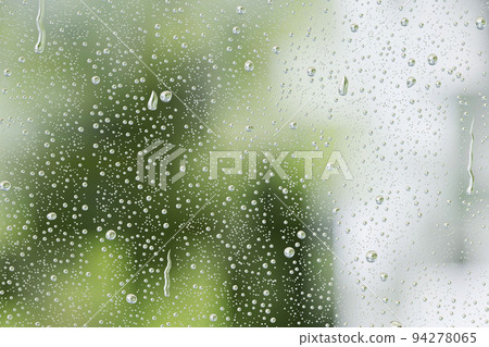 Green scenery reflected in the raindrop glass window 94278065