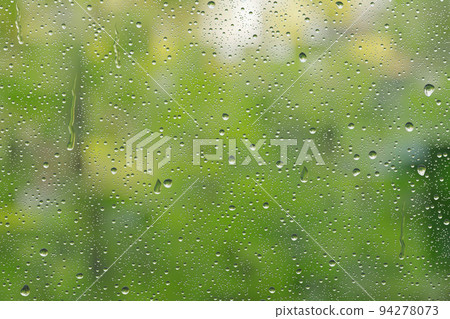 Green scenery reflected in the raindrop glass window 94278073
