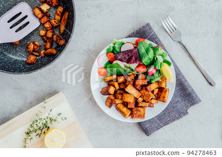 Top view healthy salad with cherry tomato, beetroot straws, spinash and lettuce leaves and portion of roasted tempeh, made of fermented soy bean on plate. Plant based protein. Healthy eating. Go vegan 94278463