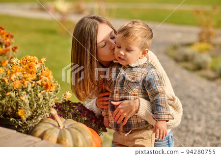 Mother kissing her cute little son outside 94280755