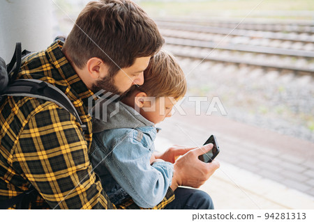 back shot of caucasian man holding children hands walking along platform going to take train 94281313