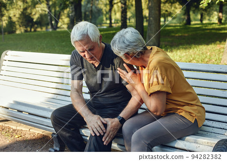 Elderly man got injured his knee during stroll with wife in park 94282382