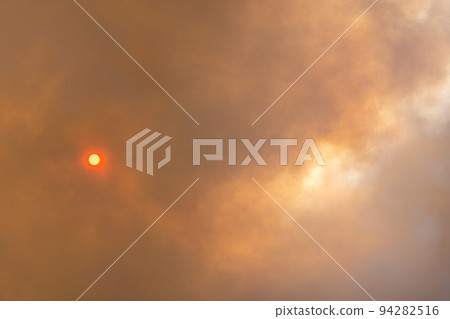 Cloud of smoke from large forest fire passing in front of sun. 94282516