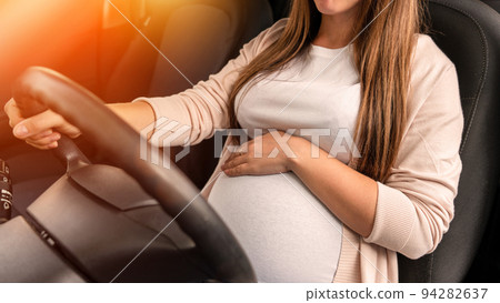 Pregnant woman driver. Beautiful smiling pregnancy woman driving car. Safety pregnant young mother drive concept. Pregnant woman driver. Beautiful smiling pregnancy woman driving car. Safety pregnant young mother drive concept. 94282637