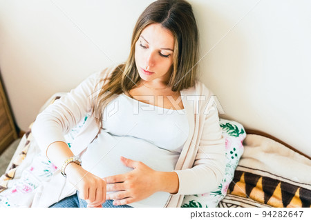 Pregnant contractions time. Pregnancy woman watching clock, holding baby belly. Childbirth time, contractions pain. Concept of pregnant, maternity, expectation for baby birth. 94282647