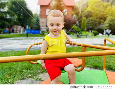 Happy toddler boy rides on a swing. Indoor playground. A cute boy of one and a half years. Selective focus 94282688
