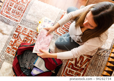 Pregnancy baby clothes. Beautiful pregnant mother with yellow baby clothes. Pregnancy woman hugging belly and packing maternity hospital bag. Concept maternity, pregnancy, childbirth. 94282734