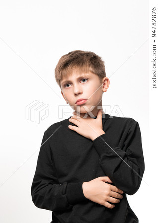 The child has a sore throat, the child is holding his throat with his hands, symptoms of throat disease. The child has a sore throat, the child is holding his throat with his hands, symptoms of throat disease. 94282876