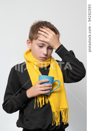 The child has a sore throat, the child is holding his throat with his hands, symptoms of throat disease. The child has a sore throat, the child is holding his throat with his hands, symptoms of throat disease. 94282893