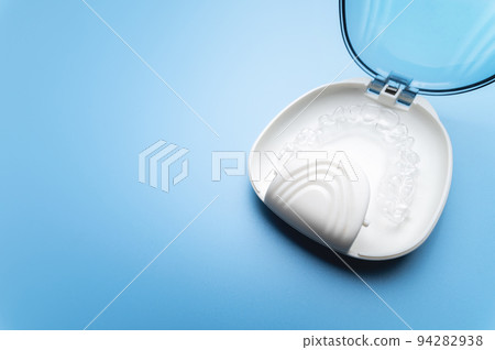 invisible plastic straighteners lie in a special orthodontic case, a white case on a blue background invisible plastic straighteners lie in a special orthodontic case, a white case on a blue background 94282938