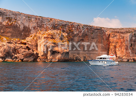 Pleasure motor boat sails near coastal rocks of Malta Pleasure motor boat sails near coastal rocks of Malta 94283034