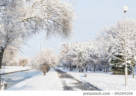 winter park, snow-covered trail above the river, beautiful willow, spruce and other trees along the track winter park, snow-covered trail above the river, beautiful willow, spruce and other trees along the track 94284104