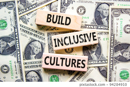 Build inclusive cultures symbol. Concept words Build inclusive cultures on wooden blocks on dollar bills. Beautiful background from dollar bills. Business build inclusive cultures concept. Copy space. 94284910