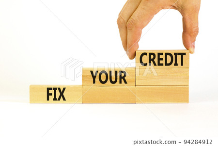 Fix your credit symbol. Concept words Fix your credit on wooden blocks on a beautiful white table white background. Businessman hand. Business, finacial and fix your credit concept. Copy space. 94284912