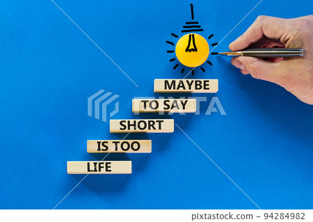 Life is short for maybe symbol. Concept words Life is too short to say maybe on wooden blocks on a beautiful blue table blue background. Businessman hand. Business motivational life or maybe concept. 94284982