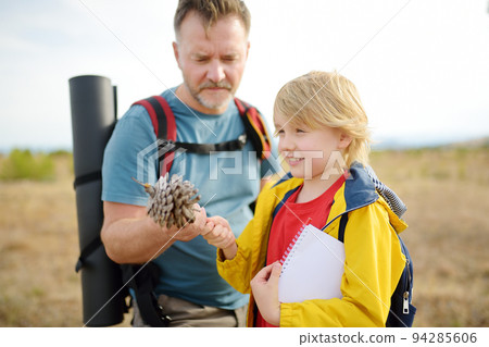 Cute schoolchild and his mature father hiking together and exploring nature. Little boy and his dad spend quality family time on summer vacation. Father's Day. Daddy and his small son 94285606