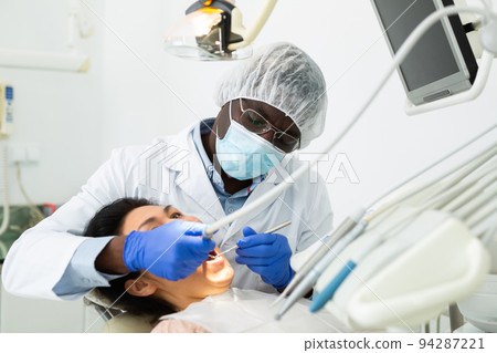 Orthodontist using tools and curing toothache of asian woman 94287221