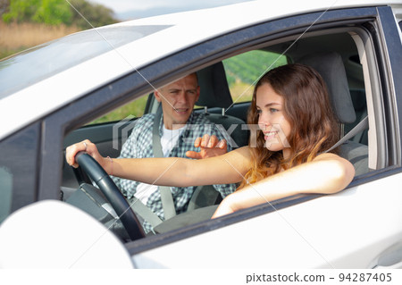 Cheerful girl driving car with boyfriend in passenger seat Cheerful girl driving car with boyfriend in passenger seat 94287405