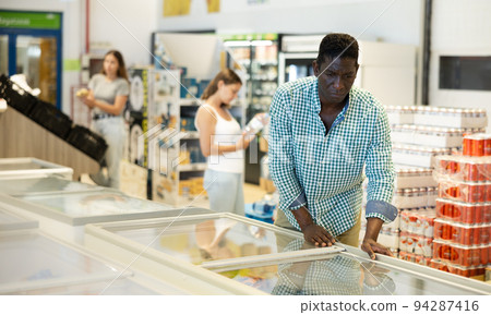 Man purchasing frozen food in grocery store Man purchasing frozen food in grocery store 94287416
