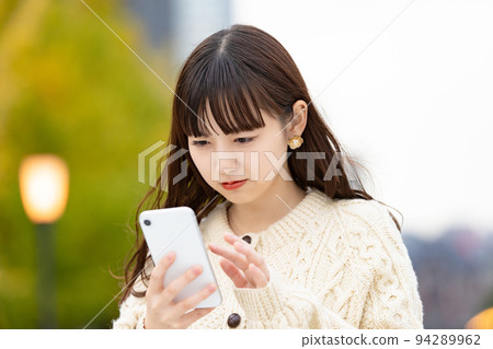 A woman looking at the smartphone screen fearfully A woman looking at the smartphone screen fearfully 94289962