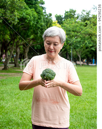 快樂的樂齡亞洲婦女微笑著站著,手上拿著有機蔬果,享受公園裡的大自然新鮮空氣,適用於老人健康飲食或素食 快樂的樂齡亞洲婦女微笑著站著,手上拿著有機蔬果,享受公園裡的大自然新鮮空氣,適用於老人健康飲食或素食 94290236